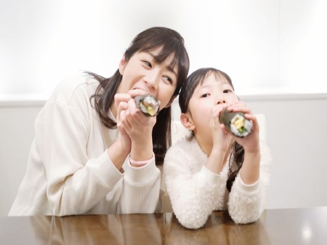 恵方巻きを親子で食べている様子の画像
