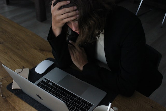 ノートパソコンの前で頭を抱える女性の画像