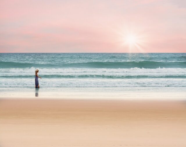 砂浜と海の境を歩く女の子の画像
