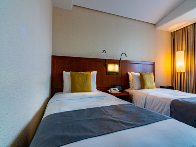 ホテルの部屋、ツインベッドが並び間接照明に照らされている画像
