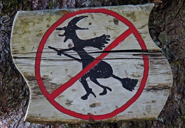 魔女の絵の上から禁止のマークが描かれている木の看板の画像